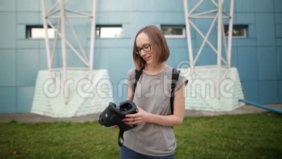 微笑的年轻女孩留着短发晚上在蓝色背景上戴着虚拟现实眼镜虚拟现实视频的预览图