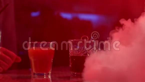 酒杯中的饮料酒吧柜台上的吸管彩灯背景下的烟雾视频的预览图