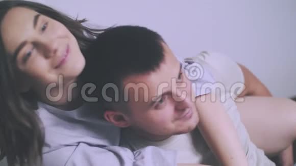 家庭幸福年轻的父母漂亮的女孩和迷人的男人穿着睡衣躺在他们一岁的孩子旁边的床上视频的预览图
