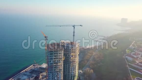 空中城市景观用两台起重机在海洋上建造一座高层摩天大楼顺时针方向太阳的光芒视频的预览图