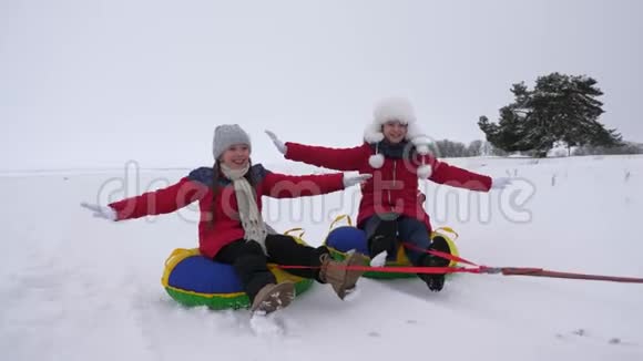 孩子们在雪地里滑在充气的雪管上用手挥动快乐的女孩在雪橇上滑过雪孩子们玩游戏视频的预览图