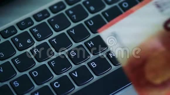 年轻人把欧元钞票和硬币放在笔记本电脑的键盘上视频的预览图