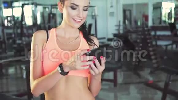 一个聪明的女孩在现代化的健身房里玩滑稽的自拍视频的预览图