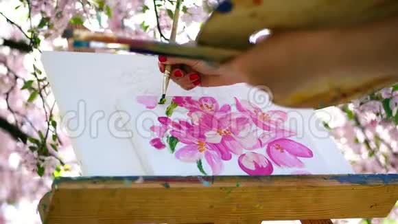 特写画家画了一幅春暖花开的苹果园里的花她用画笔作画用调色板作画视频的预览图