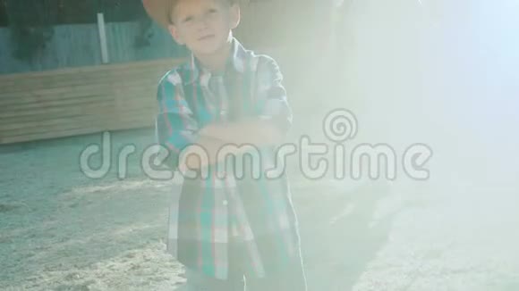 阳光下一个时髦的小牛仔站在纯种马旁边慢慢地视频的预览图
