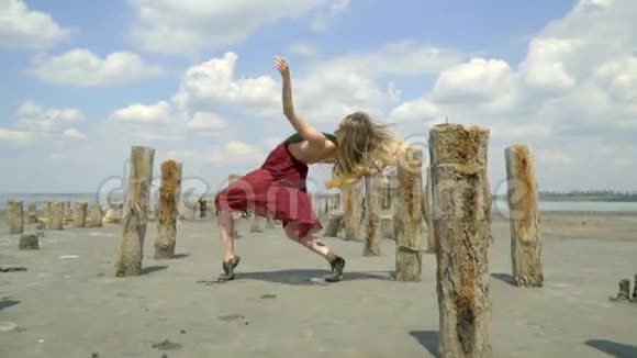 一个穿着裙子的金发美女闻着泥浆异常地沿着河口在废弃的盐池里跳舞视频的预览图