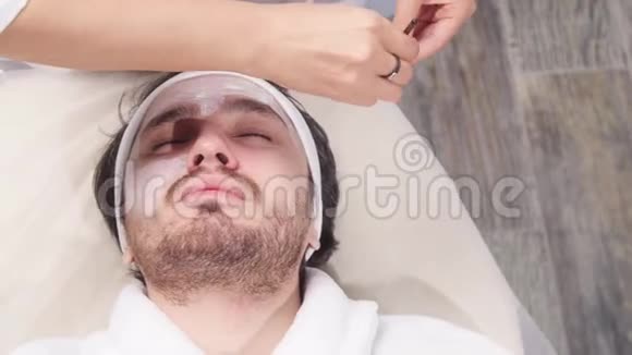 美容师在一个年轻人脸上戴面具视频的预览图