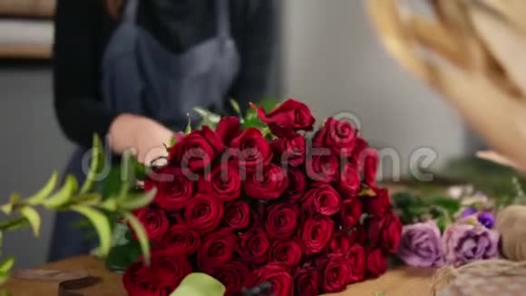 年轻迷人的女花店在花店里布置一束美丽的红玫瑰慢镜头视频的预览图