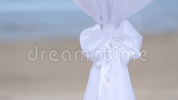 婚礼前海滩上白色织物和鲜花的婚礼装饰视频的预览图
