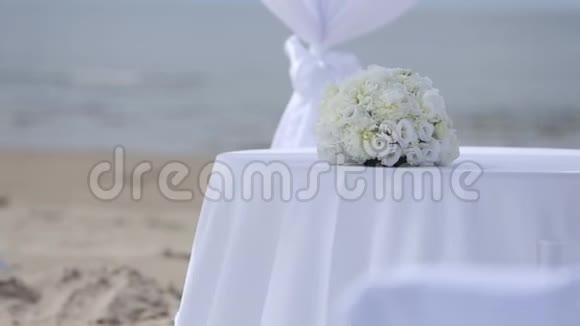 婚礼前海滩上白色织物和鲜花的婚礼装饰视频的预览图