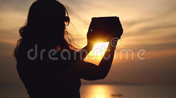 女孩在美丽的海景背景上的手机摄像头上自拍阳光明媚的灯光反射在大海上视频的预览图