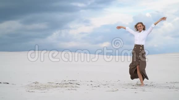 美丽的女孩在沙漠中央在云层的映衬下翩翩起舞视频的预览图