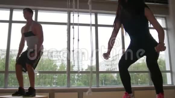 运动的女人和肌肉发达的男人健身教练在健身房锻炼时做盒子跳跃运动视频的预览图