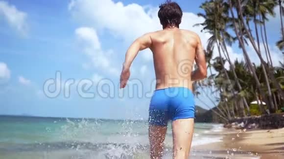 阳光明媚的一天年轻人在海滩上奔跑缓慢地溅起海浪1920x1080视频的预览图