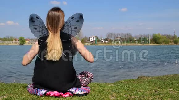 女孩起飞蝴蝶翅膀继续在平静的水旁边的莲花位置冥想视频的预览图