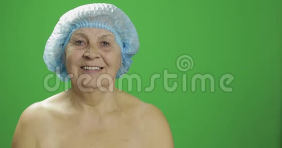 戴着防护帽微笑的老年女性整形外科医生检查女性面部视频的预览图