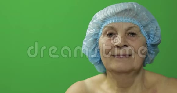 戴着防护帽微笑的老年女性整形外科医生检查女性面部视频的预览图
