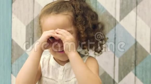 一个长着红色卷发的漂亮小可爱的小女孩展示了一个望远镜展示了一个问候的标志在一个视频的预览图
