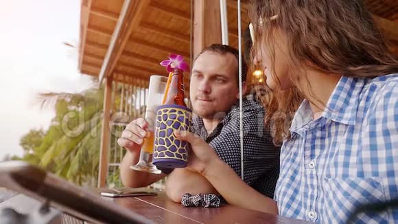 美丽的浪漫晚餐在海滩咖啡馆夫妇蜜月喝水果鸡尾酒和啤酒附近的海洋慢慢慢慢视频的预览图