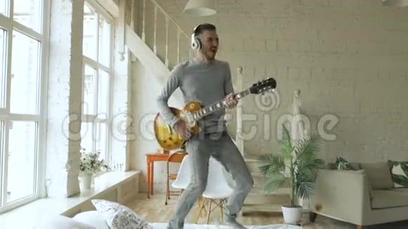 滑稽胡子男在床上跳舞在家里的卧室里唱歌和弹电吉他视频的预览图