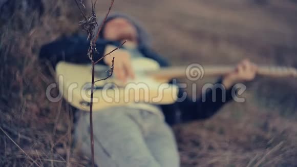 日落时分一个男人躺在橡树下弹吉他视频的预览图