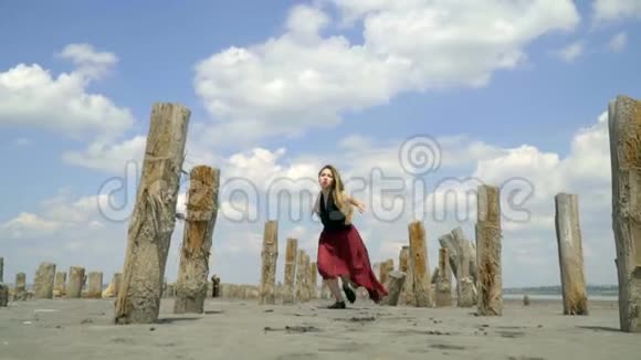 一个美丽的金发女郎穿着一件被泥污染污的裙子沿着河口在废弃的盐池中跳舞底部的景色视频的预览图