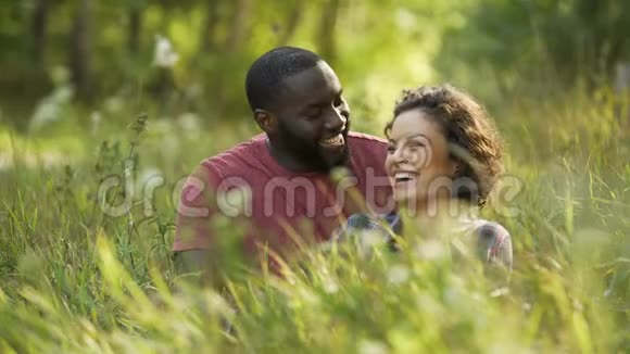 多种族夫妇在草地上嬉笑聊天户外约会视频的预览图