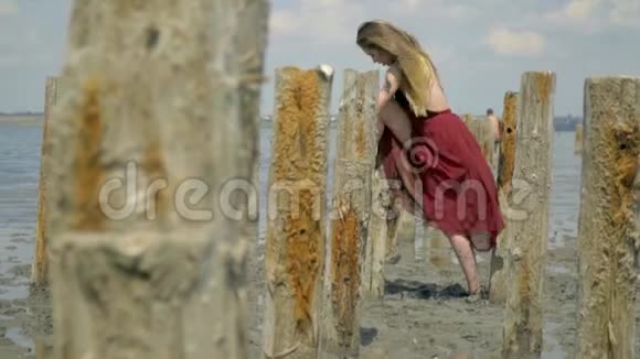 一个身长发的金发碧眼穿着一件红色连衣裙一只脚站在风的吹拂下中间视频的预览图
