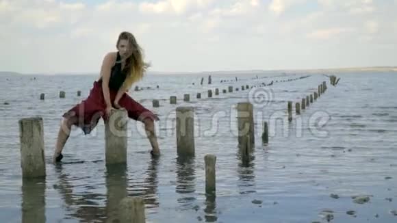 金发碧眼穿着一件红色的衣服穿着一身泥摆着一条腿抓住盐池的木柱视频的预览图