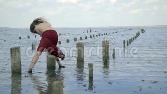 金发碧眼穿着一件红色的衣服穿在泥里站在河口拿着盐池的木柱后面视频的预览图