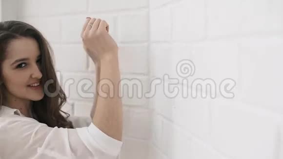 年轻的微笑女孩穿着空白的t恤背景中的砖墙视频的预览图