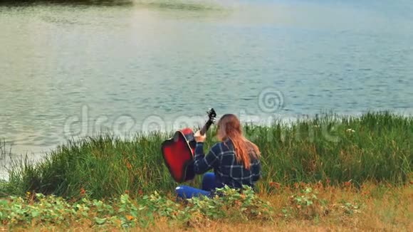一个年轻的辛波蒂克纳亚女孩弹吉他当太阳越过地平线时她很孤独视频的预览图