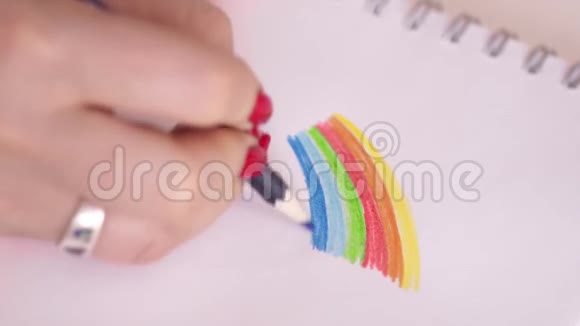 彩虹那个女人画了一支彩虹色铅笔红色指甲的女人在白纸上画了一道明亮的彩虹视频的预览图
