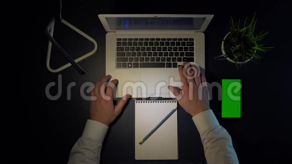 坐在桌旁工作的人用笔记本电脑和电话视频的预览图