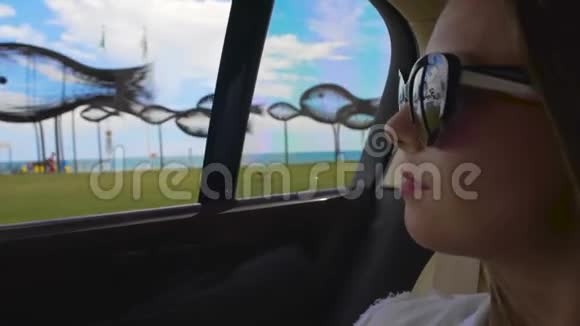 汽车旅行年轻女子从窗口欣赏风景在海洋度假城市度假视频的预览图
