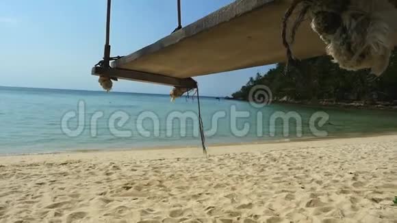 一个木制的秋千座椅挂在海边的椰树上海滩干净天空湛蓝慢动作1920x1080个视频的预览图