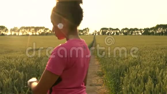 混血非裔美国少女女青年使用智能手表跑步在大麦地跑步视频的预览图