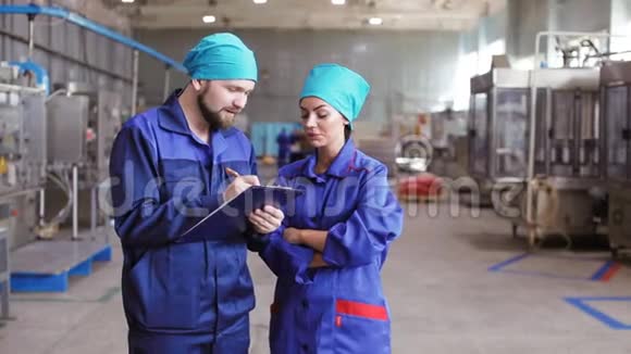 两名工人拿着剪贴板在工厂检查机器视频的预览图
