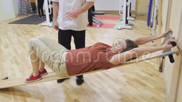 理疗师帮助老年妇女旋转腿在健身房做运动健康体操活跃的人视频的预览图