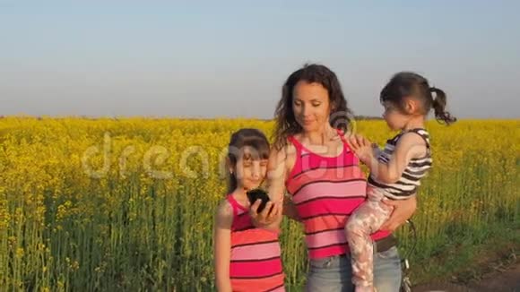 有孩子的快乐母亲在大自然中被拍摄家庭在本质上是自我的有孩子的女人在黄色的田野里视频的预览图