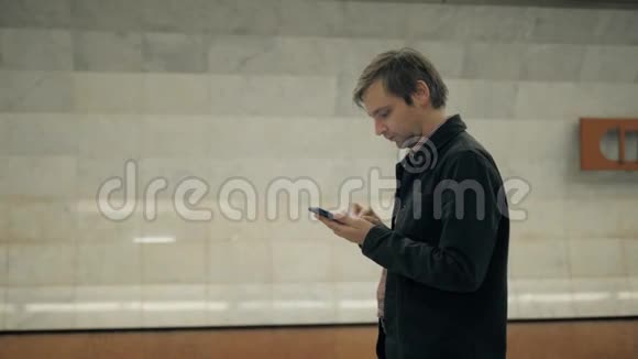 微笑男子地铁地下行走在列车前与手机智能手机应用程序交谈视频的预览图