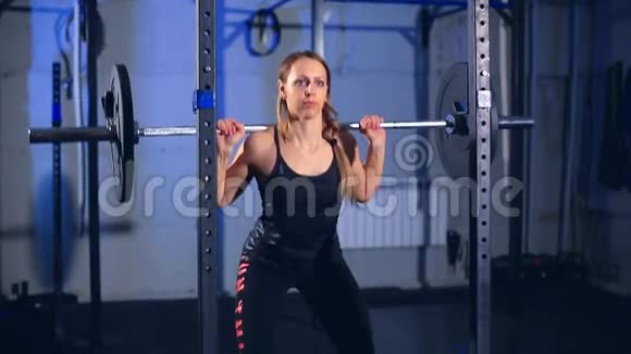 健身女人在健身房里做杠铃蹲后景正面视图视频的预览图
