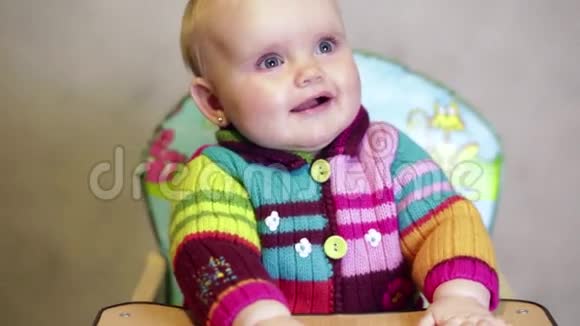 快乐的女婴坐在孩子们椅子上微笑着视频的预览图