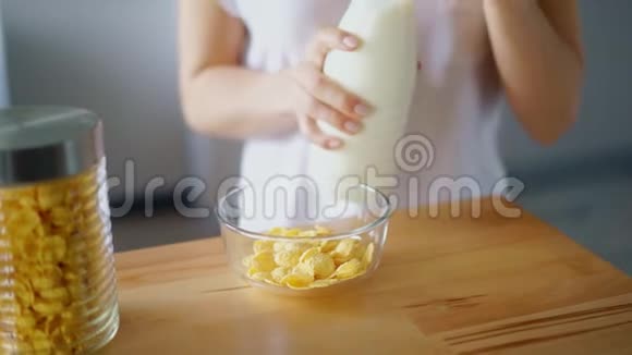 女人把牛奶倒进玻璃碗里的玉米片准备早餐视频的预览图