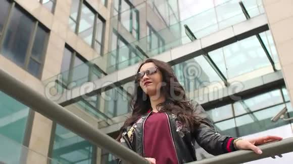 一个城市女孩在玻璃摩天大楼附近的肖像视频的预览图