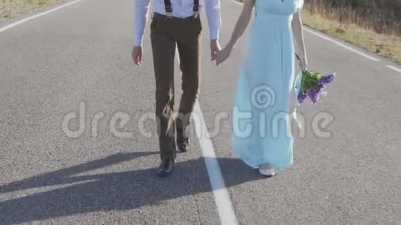 一对时髦的年轻夫妇手牵手走在山间的路上视频的预览图