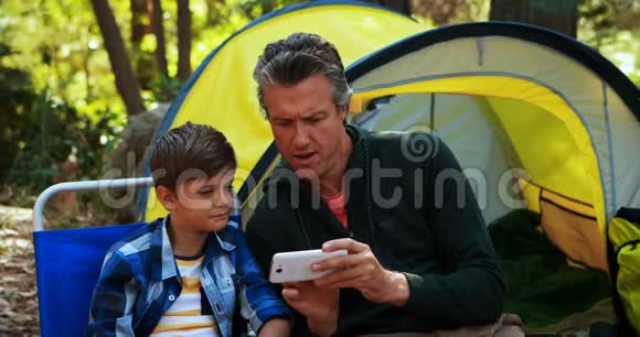 父子俩在帐篷外用手机视频的预览图
