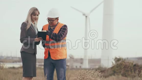 建筑业一位身穿反光背心和头盔的承包商与一位带数字平板电脑的商务女性合作视频的预览图