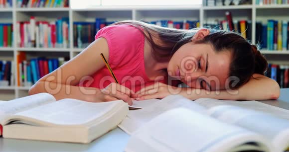 疲倦的女学生在图书馆里做作业视频的预览图