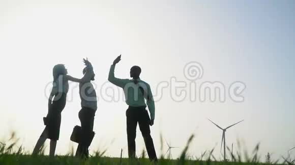 一群穿着商务服的人在风力发电机的背景下表现出高5级动作慢视频的预览图